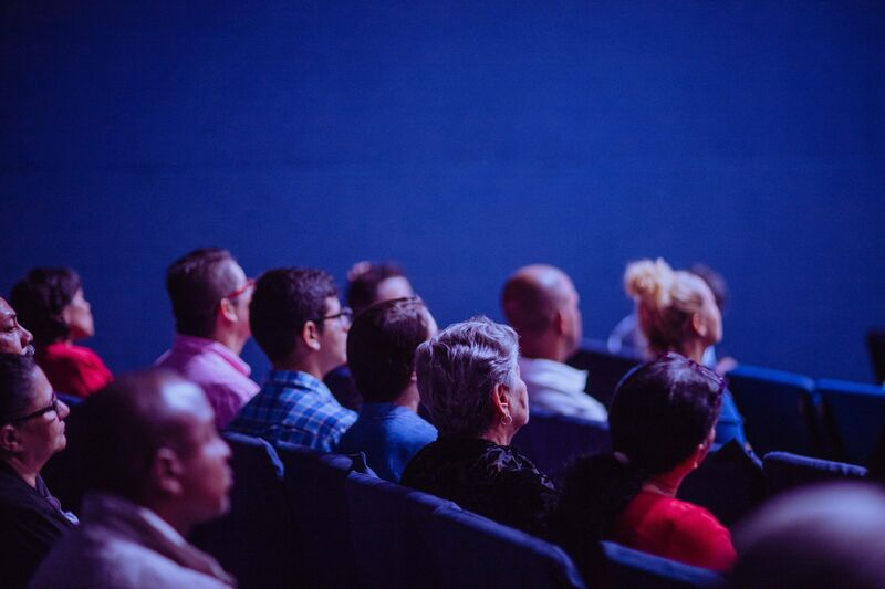 Menschen sitzen im Publikum und hören einem Vortrag zu.
