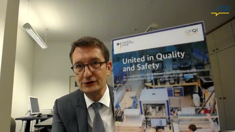 Stefan Schnorr (BMWi) präsentiert die neue Publikation "United in Quality and Safety". Er hält sie in die Kamera.